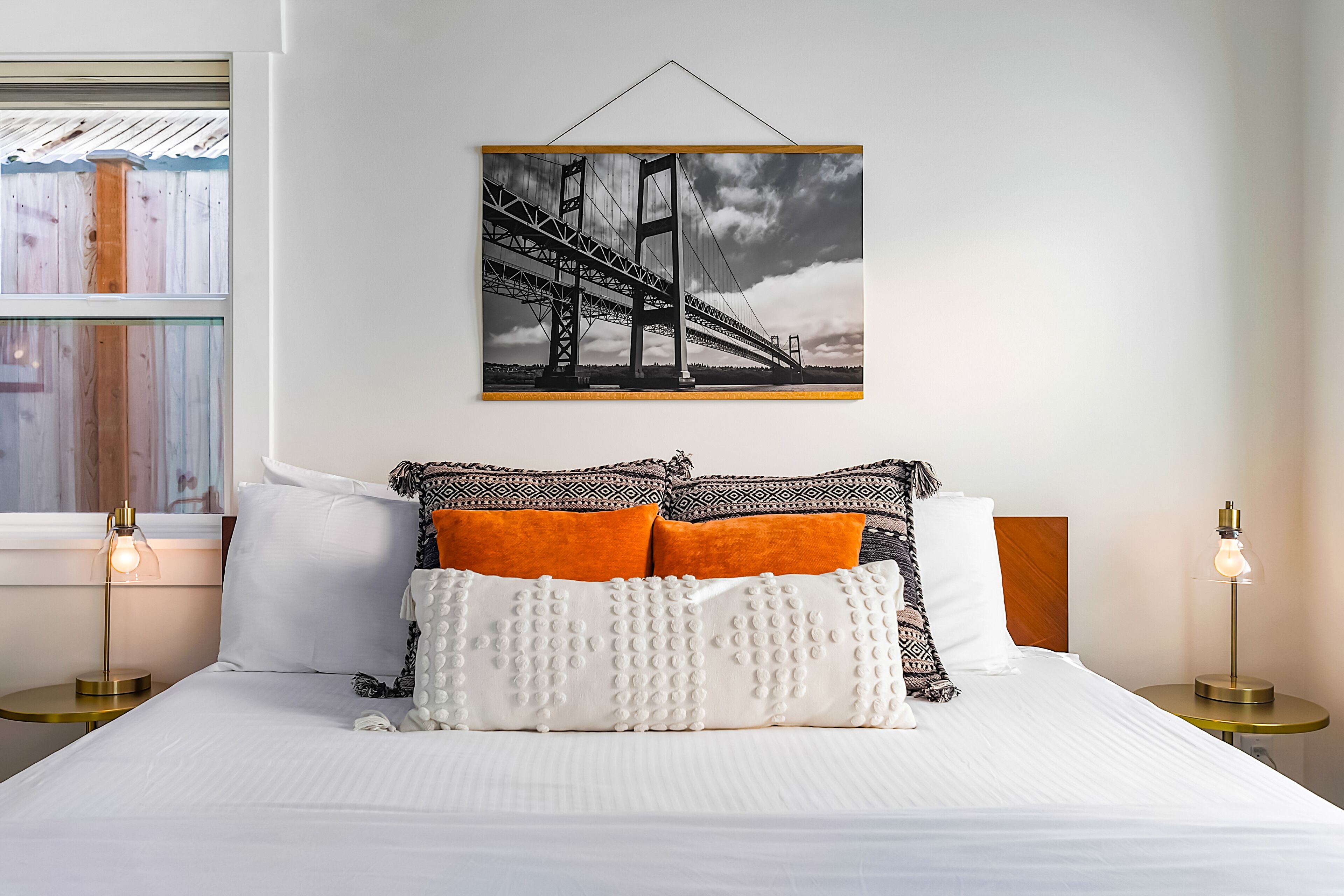 Ein Hotelzimmer mit einem großen Bett, zwei Nachttischen und einem an der Wand hängenden Bild einer Brücke.