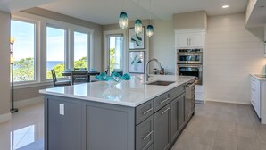 Una cucina moderna con una grande isola, elettrodomestici in acciaio inossidabile e illuminazione a sospensione.