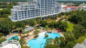 Un grande hotel con diversi piani, una piscina e vegetazione circostante.