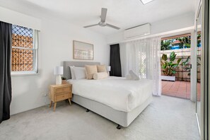 Ein Schlafzimmer mit Bett, Nachttisch, Lampe und Deckenventilator.