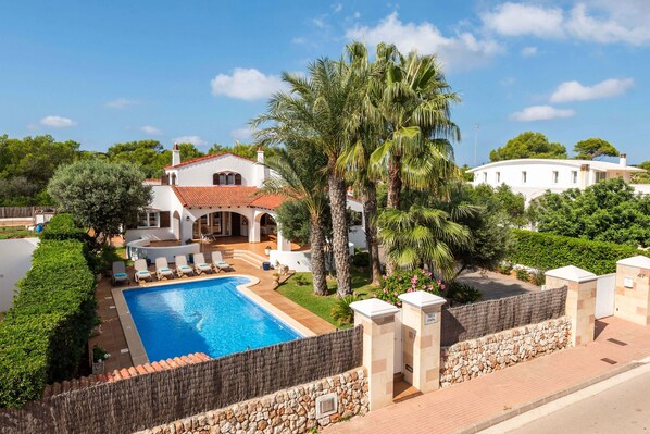 Une villa dotée d’une piscine, de palmiers et d’un jardin bien entretenu.