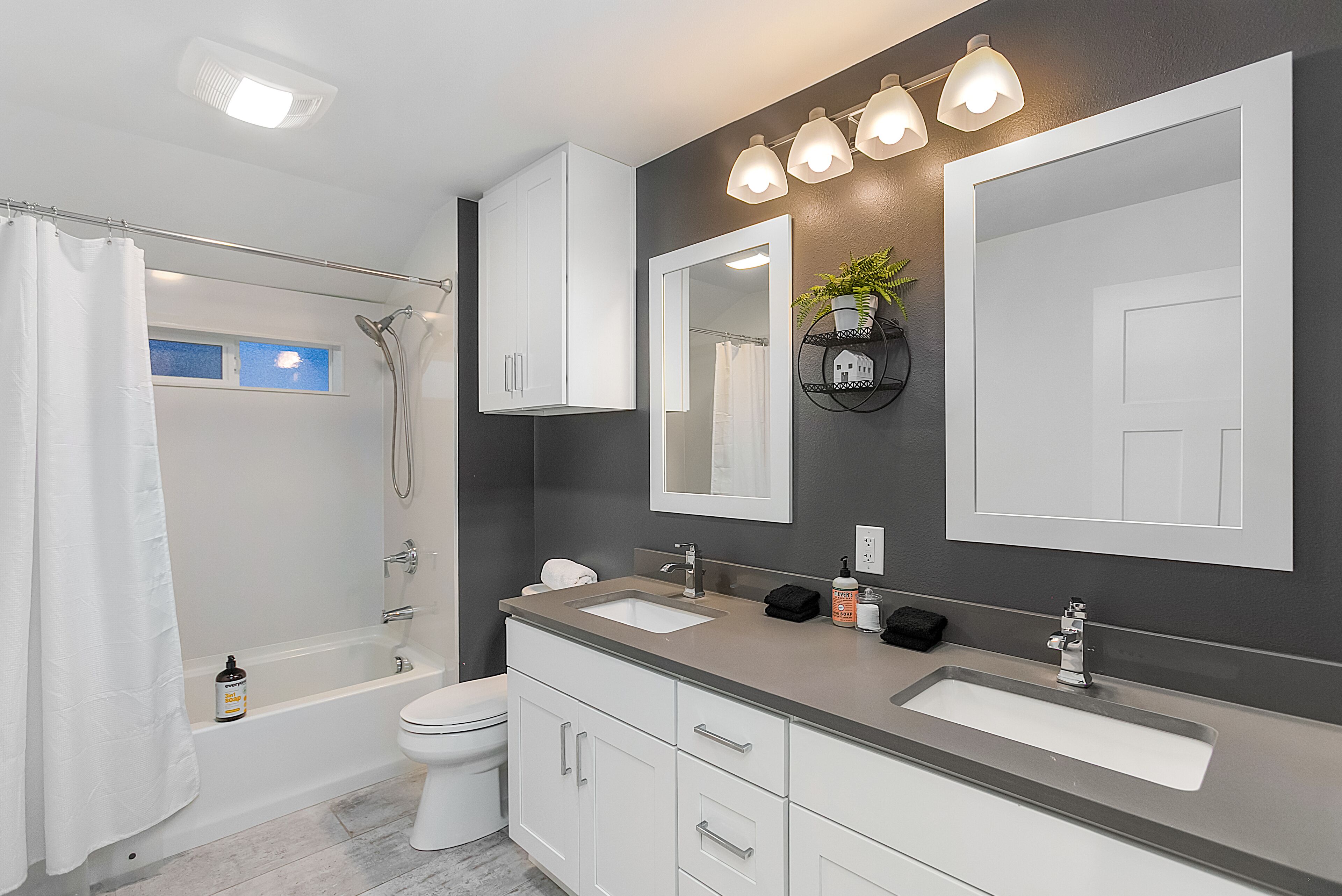 Et moderne badeværelse med badekar, toilet og håndvaskarrangement med vask og spejle.