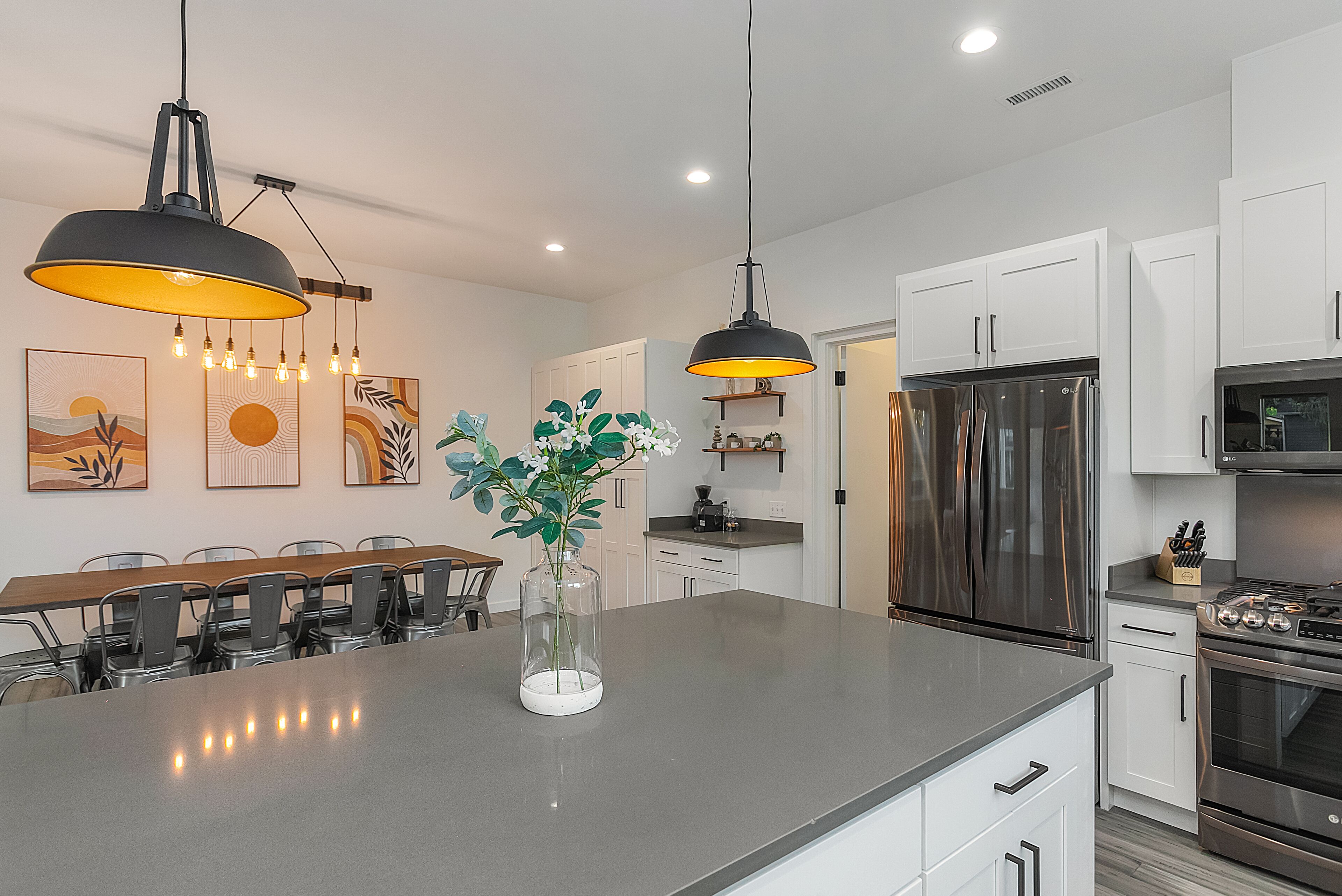A modern kitchen with a central island, stainless steel appliances, and pendant lighting.