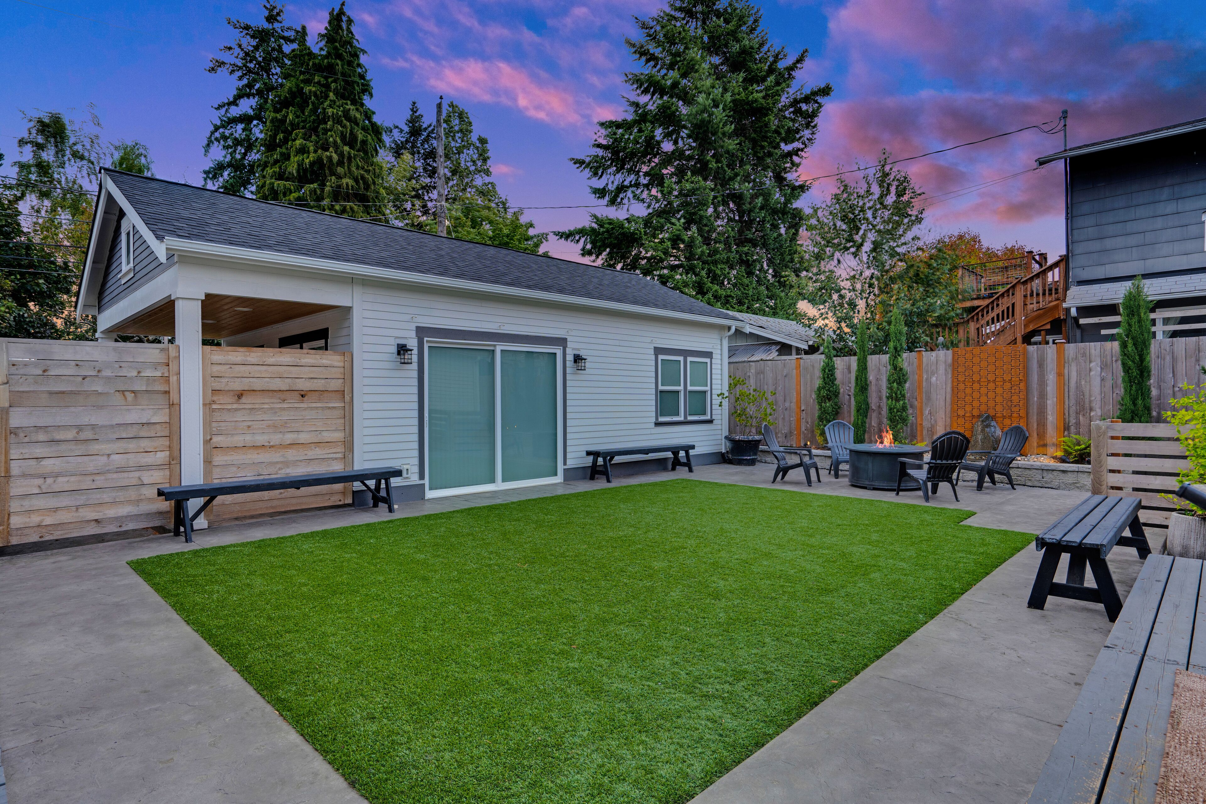 A backyard with a covered patio, a fire pit, and outdoor seating.