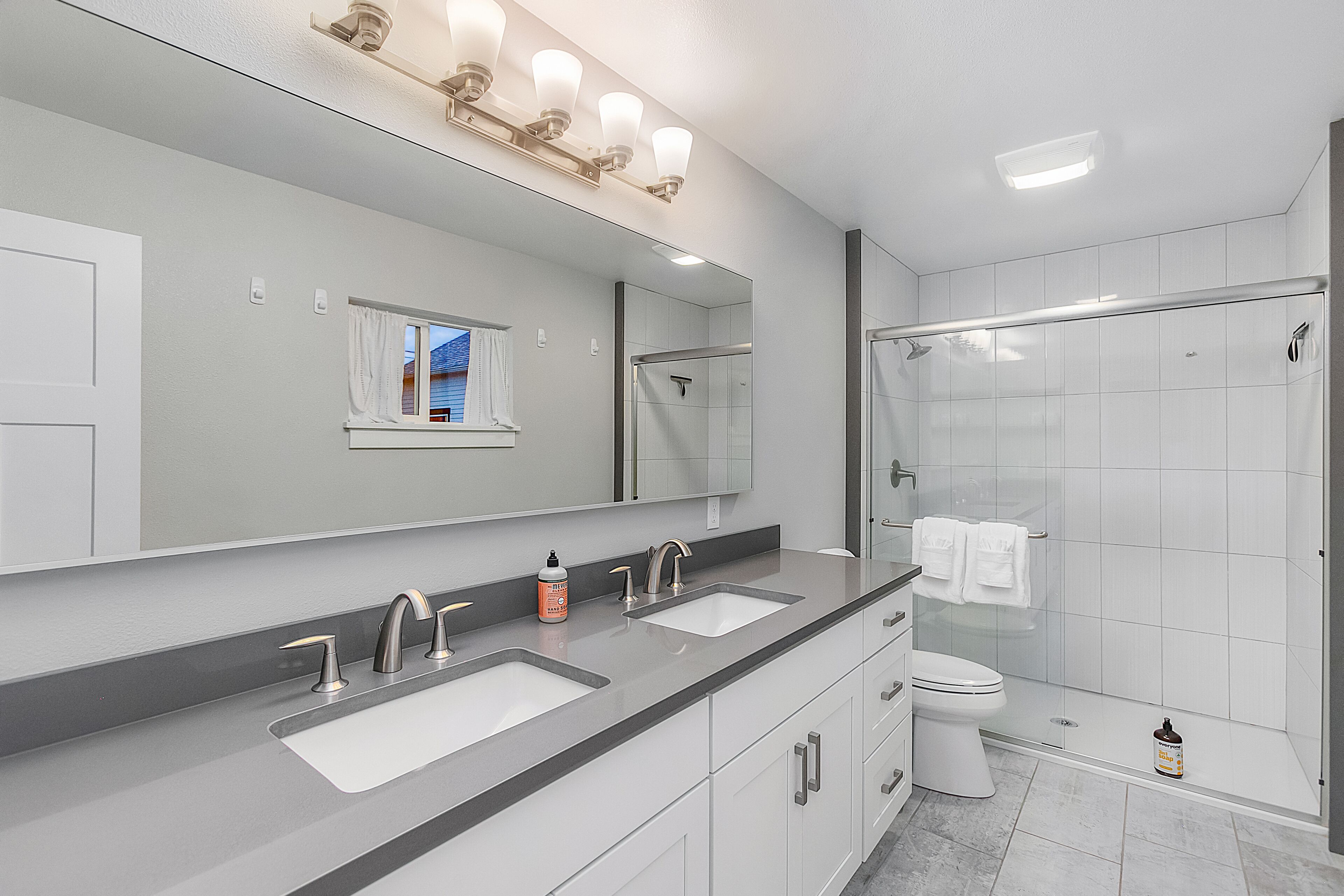 Un bany modern amb dues dutxes, un mirall gran i una cabina de vidre.