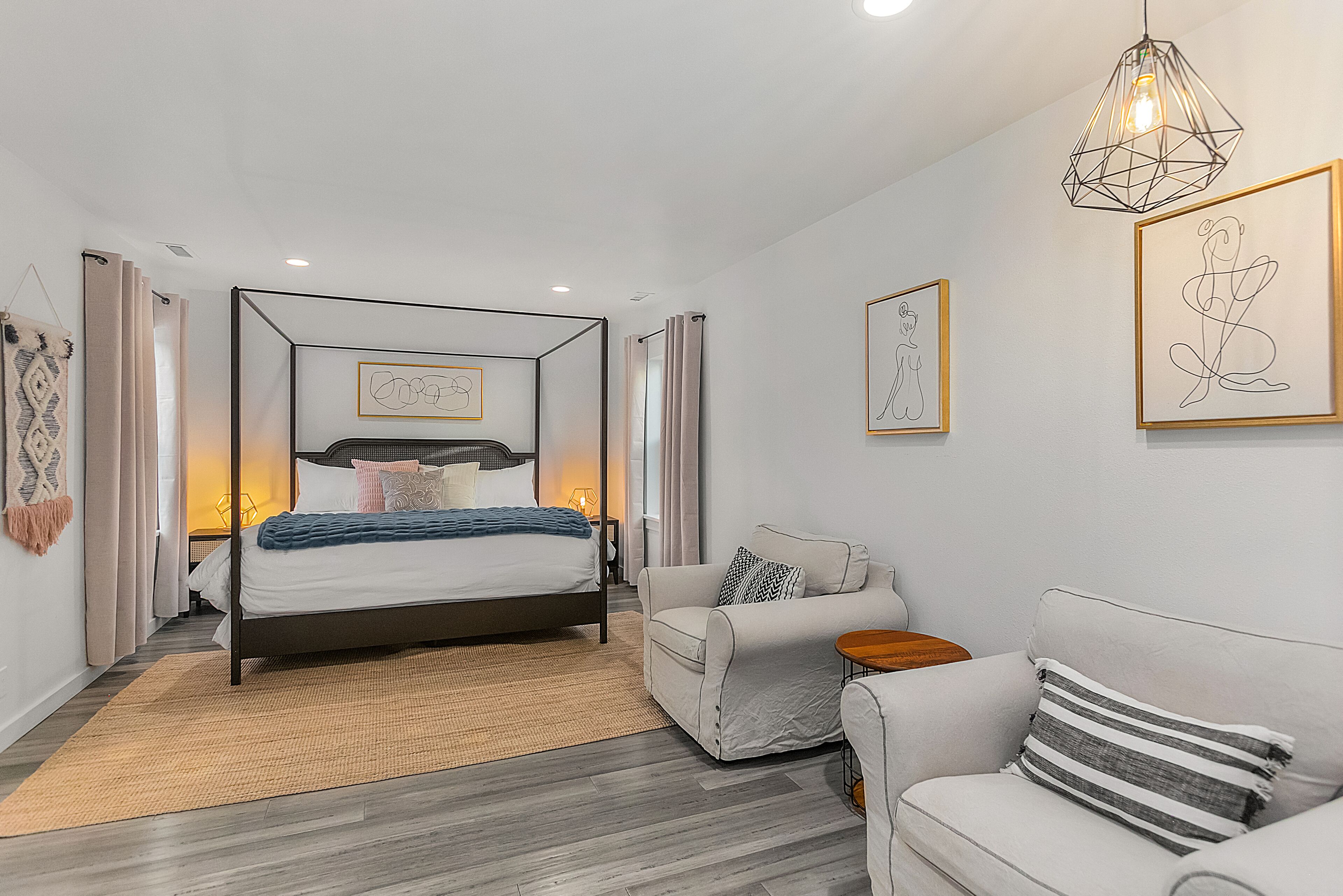 A modern bedroom with a four-poster bed, a white sofa, and a small side table.