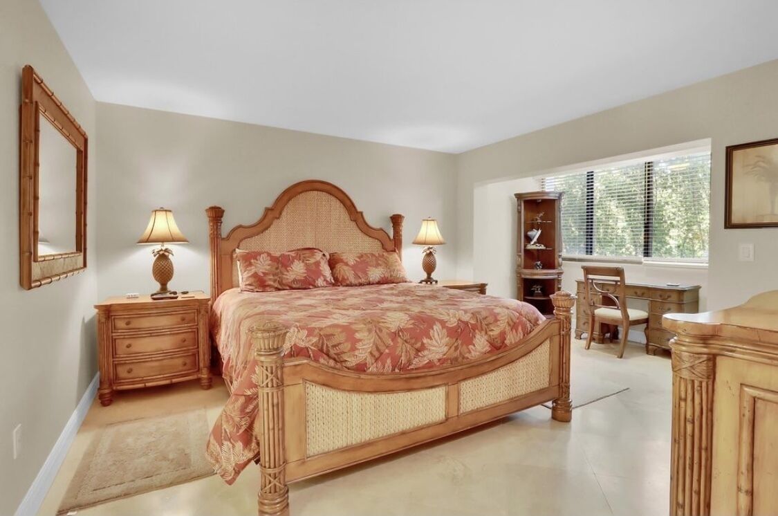 Une chambre à coucher avec un grand lit, des tables de chevet avec des lampes, un bureau et une chaise.