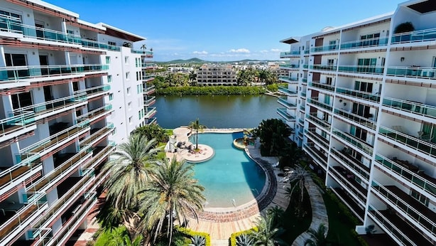 A high-rise hotel with multiple balconies, a central swimming pool, and surrounding greenery. - Pacifika Marina Mazatlan by Partnerhost (Mazatlán)