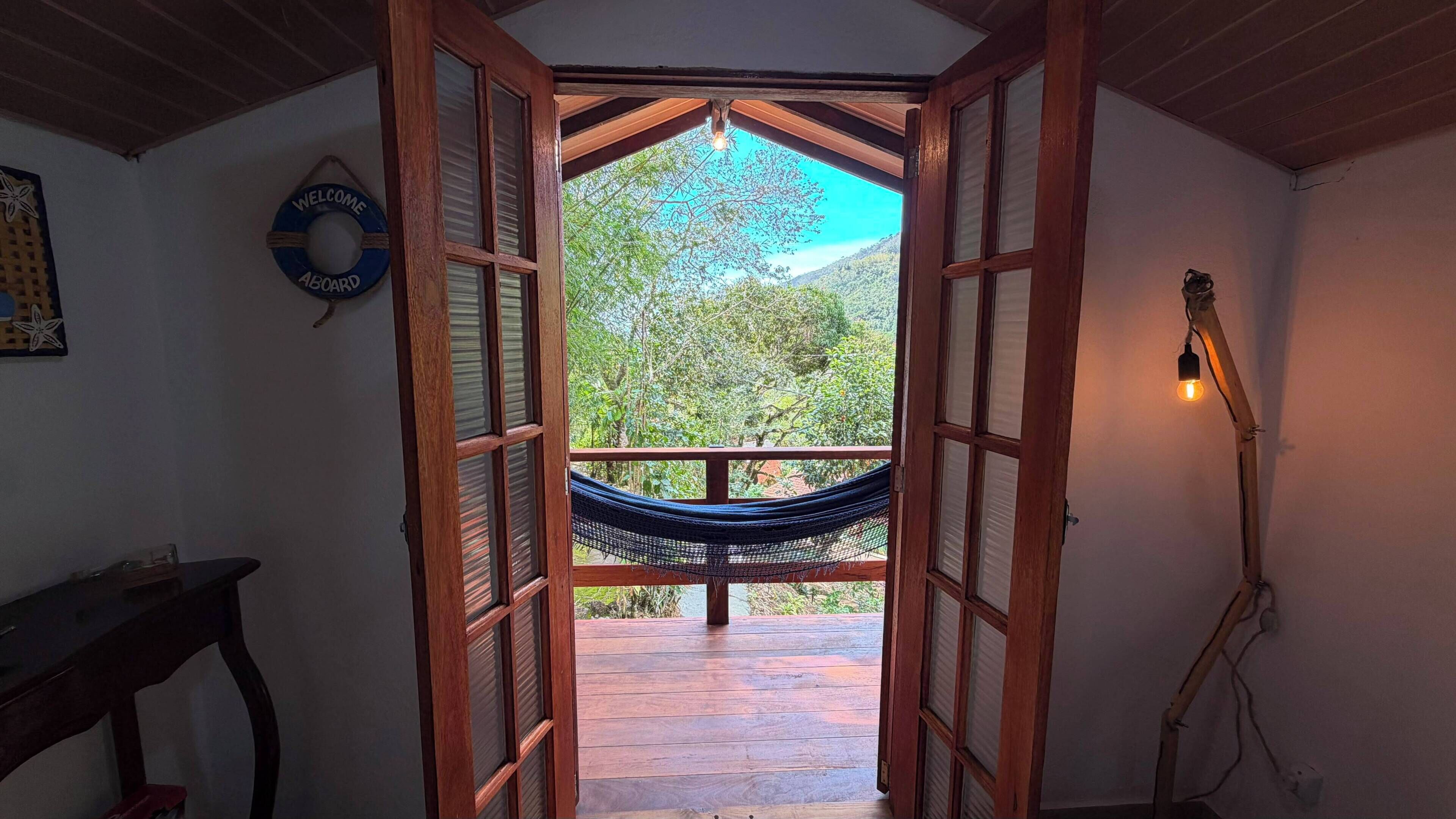 A doorway leading to an outdoor area with a hammock, a welcome sign, and a guitar.