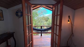 A doorway leading to an outdoor area with a hammock, a welcome sign, and a guitar.