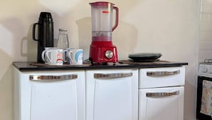 A kitchen with a white cabinet, a red blender, a coffee maker, and a kettle. - Pedaço de Céu Chalet: In the woods, 5 minutes from the beach (Paraty)