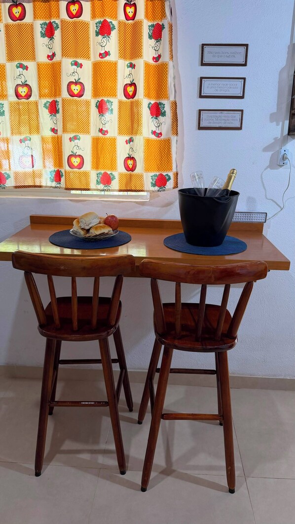 Un comedor con una mesa de madera y dos sillas, una botella de champán y un plato de comida.