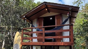 A two-story wooden building with a balcony, a bench, and a surfboard. - Pedaço de Céu Chalet: In the woods, 5 minutes from the beach (Paraty)