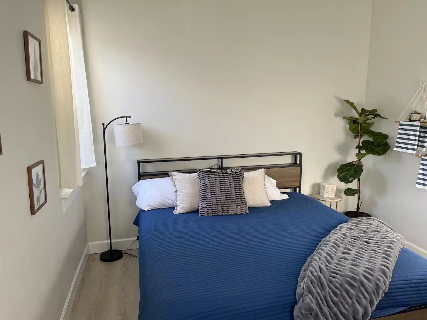Ein Schlafzimmer mit Bett, Nachttisch, Lampe und einer Zimmerpflanze.