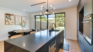 A modern kitchen with a large island, built-in appliances, and a dining area with a round table and chairs.
