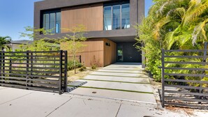 A modern building with a flat roof, large windows, and a concrete pathway leading to the entrance.