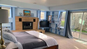 Quarto com cama, televisão, lareira e porta de vidro deslizante para o exterior.