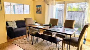 Uma sala de jantar com mesa de madeira, quatro cadeiras, um sofá e um tapete.