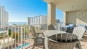 A balcony with outdoor furniture, a view of the ocean, and high-rise buildings in the background. - •Beach Access•Pools•Gulf View•Balcony•Beach Gear•King•5min Walk to Beach•W/D•Gym (Miramar Beach)