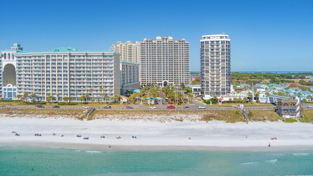 A beachfront hotel with multiple high-rise buildings, a sandy beach, and clear blue skies. - •Beach Access•Pools•Gulf View•Balcony•Beach Gear•King•5min Walk to Beach•W/D•Gym (Miramar Beach)