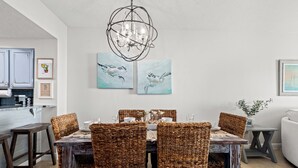 A dining area with wicker chairs, a chandelier, and artwork on the walls. - •Beach Access•Pools•Gulf View•Balcony•Beach Gear•King•5min Walk to Beach•W/D•Gym (Miramar Beach)