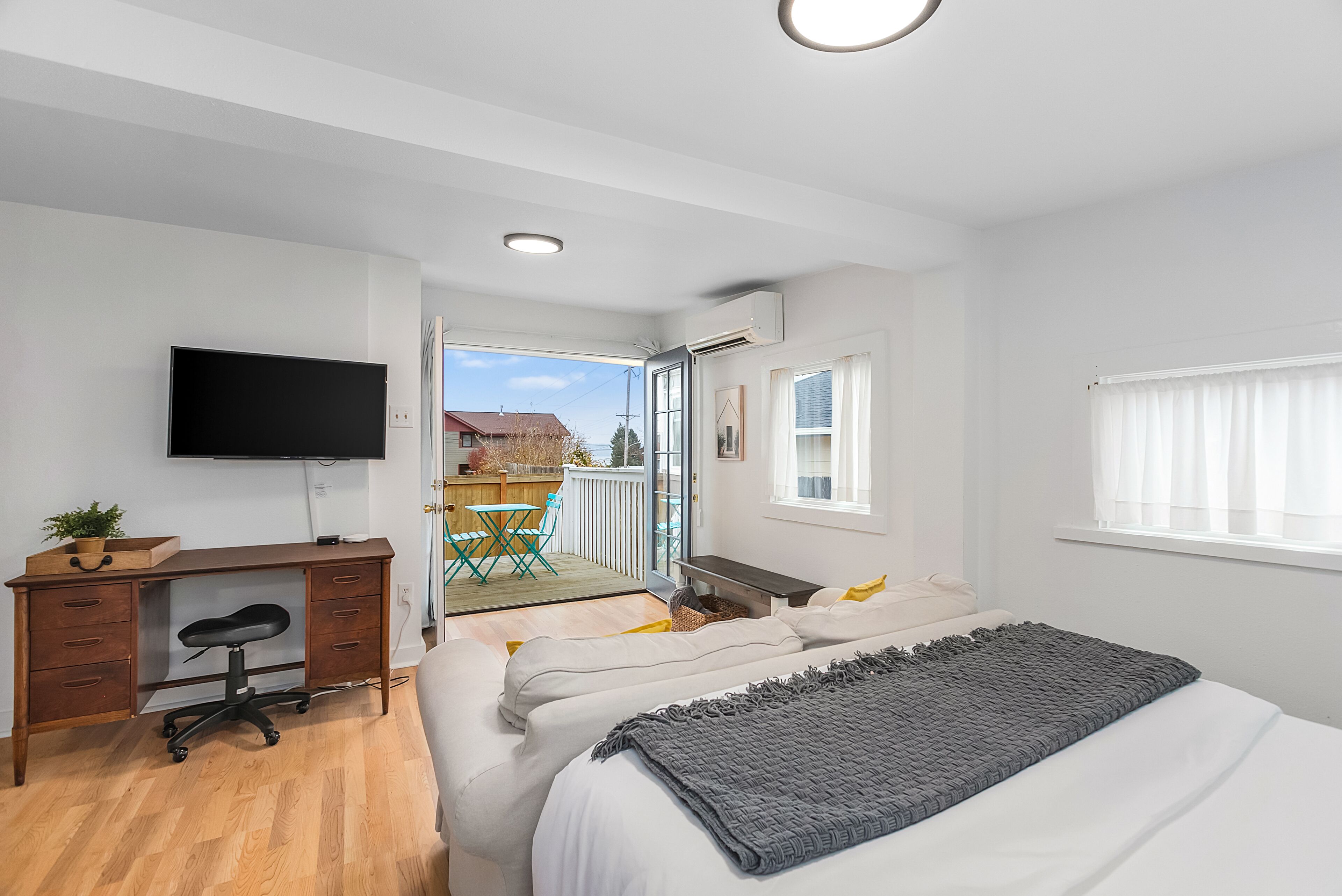 Um quarto moderno com cama, escrivaninha e televisão.