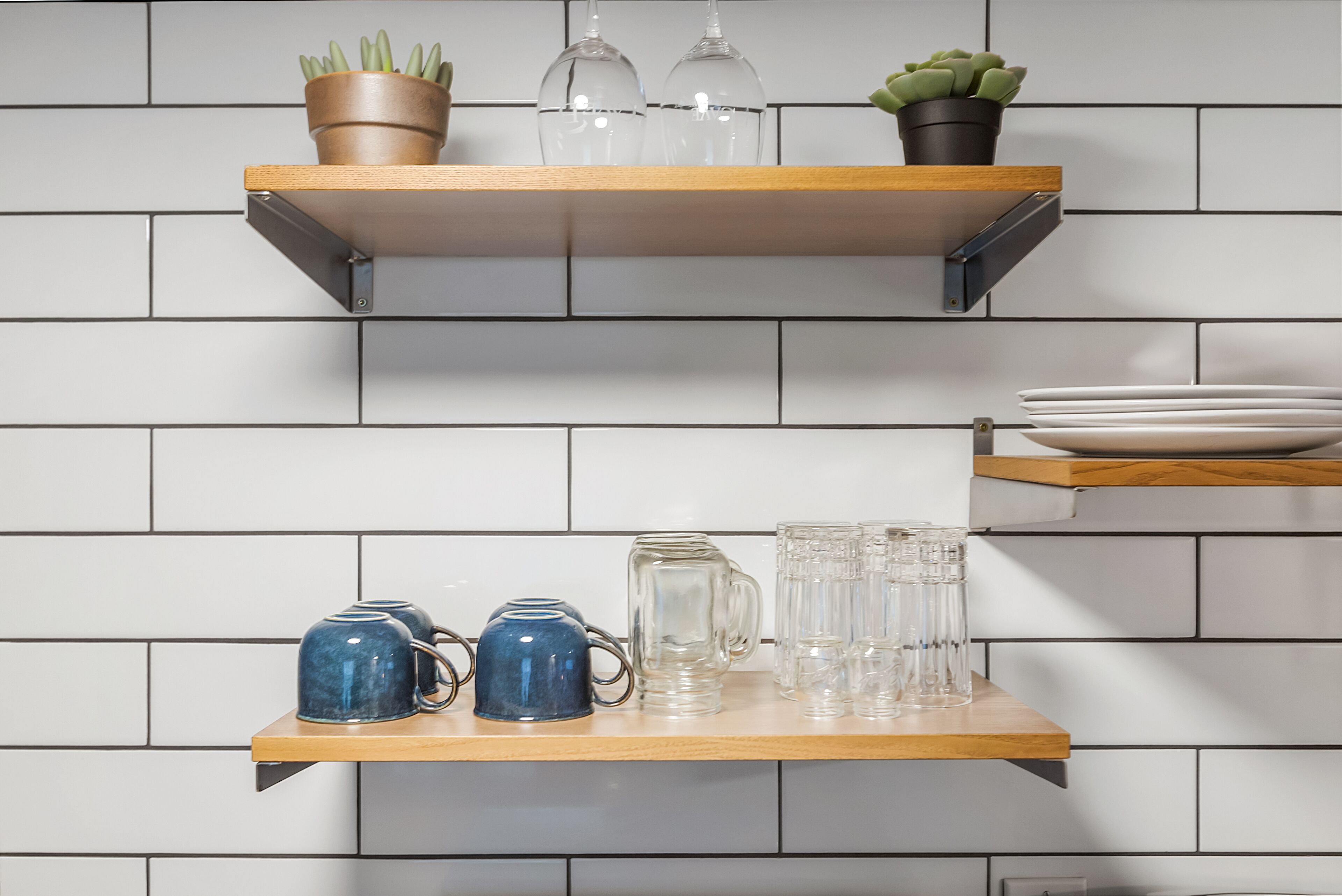 Two wooden shelves against a tiled wall, each holding various items.
