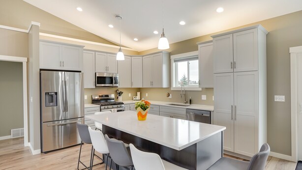 A modern kitchen with a central island, stainless steel appliances, and white cabinetry.