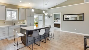 A modern kitchen with a central island, bar stools, and pendant lighting.