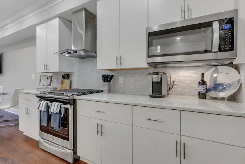 A modern kitchen with white cabinets, stainless steel appliances, and a tiled backsplash.