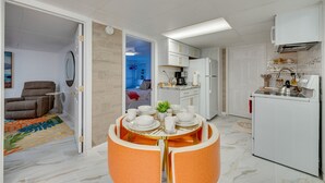 A compact living space with a dining area, kitchen, and a bedroom visible through an open door.