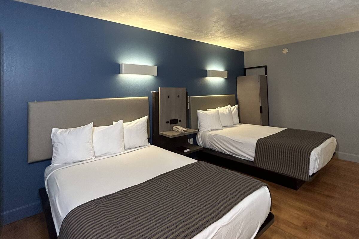 Une chambre d’hôtel avec deux lits, un plancher en bois et un mur bleu.