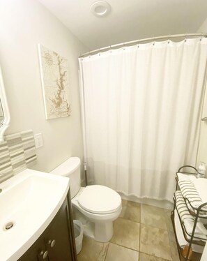 A bathroom with a toilet, a sink, a shower curtain, and a towel rack. - Keowee Key's Stylish Charm (Salem)