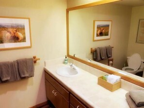 Une salle de bain avec un grand miroir, un lavabo, des toilettes et des serviettes.