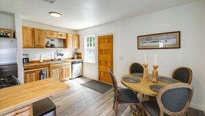 A kitchen with wooden cabinets, a refrigerator, a dishwasher, and a dining area with a wooden table and chairs.