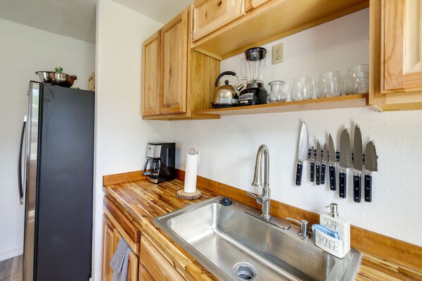 A kitchen with wooden cabinets, a stainless steel sink, a refrigerator, a coffee maker, and a knife block. - Charming Hamilton Hideaway: Half-Mi to Main St! (Hamilton)