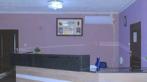 A reception area with a reception desk, a framed picture on the wall, and a door to the right.