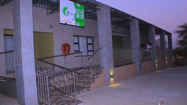 A building with a covered entrance, a staircase, and a signboard.