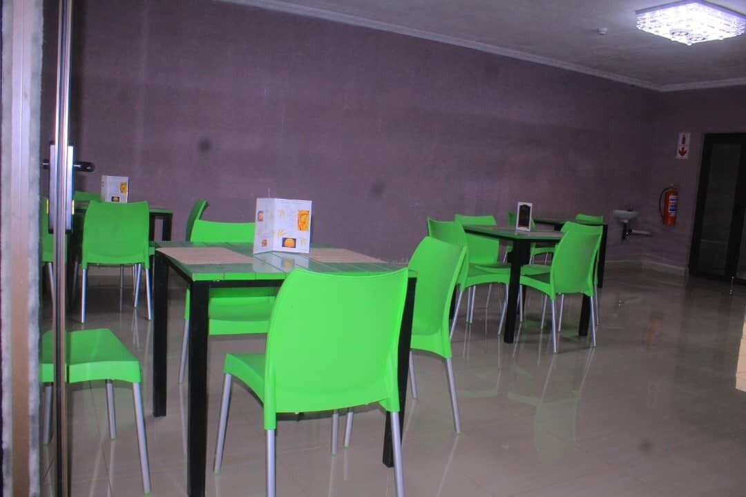 A room with green chairs and tables, a fire extinguisher, and a door.