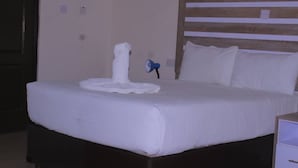 A neatly made bed with white linens and a wooden headboard.