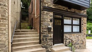 Un bâtiment en pierre avec une porte noire et une fenêtre à vitres dépolies.