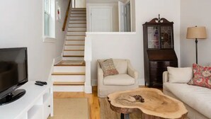 Un salon avec un escalier, un téléviseur, une table basse en bois et un meuble.