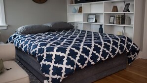 Un dormitorio con cama, una estantería blanca y un reloj en la pared.