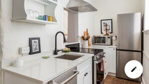 Una cocina moderna con armarios blancos, un refrigerador de acero inoxidable, un microondas y una estufa.