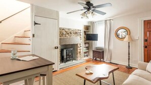 A living room with a fireplace, a ceiling fan, a television, and a sofa.