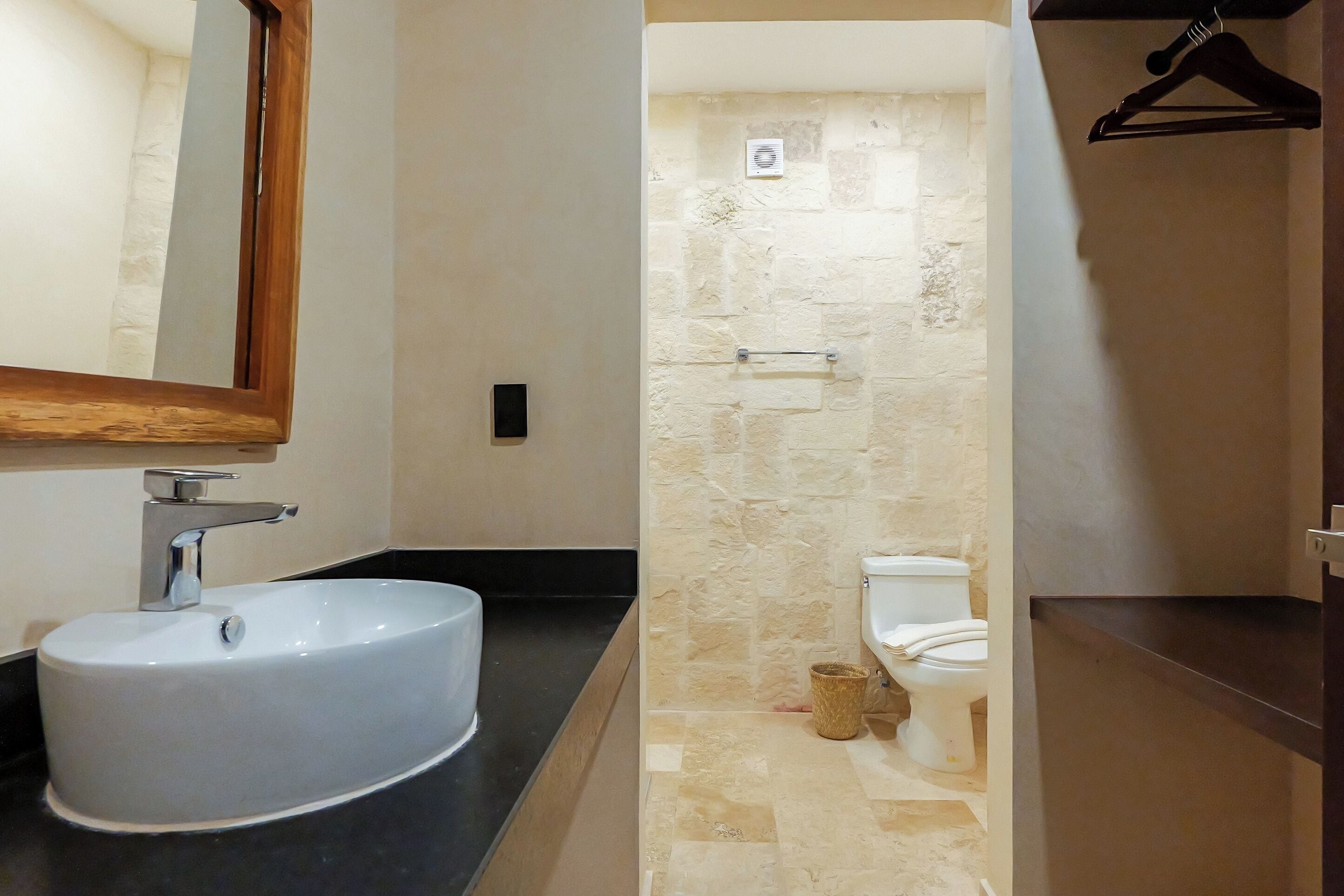 A bathroom with a white sink, a mirror, a toilet, and a towel rack.