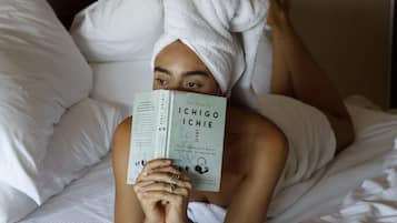 Une personne allongée sur un lit, avec un livre intitulé « Le Livre d’Ichi et de Chi » et une tasse.