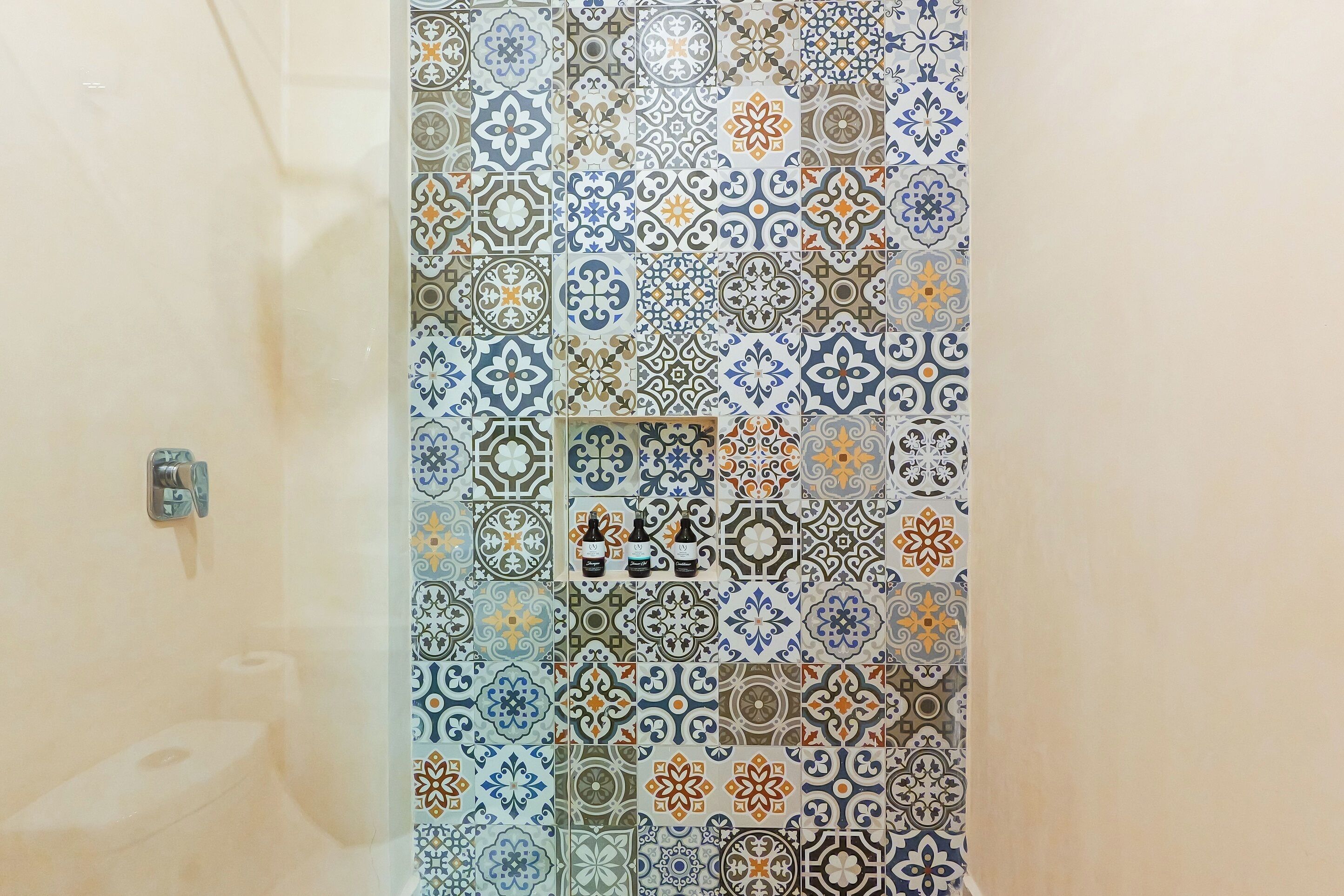 Een badkamer met een betegelde douchewand met verschillende geometrische patronen.