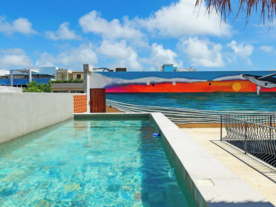 A clear blue sky, a swimming pool, and a view of the ocean with a sunset.