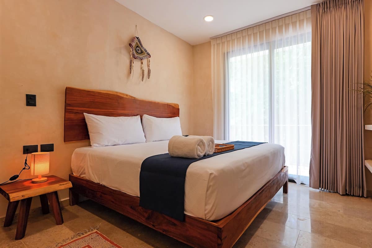 A neatly made bed with a wooden headboard, a bedside lamp, and a decorative wall hanging.